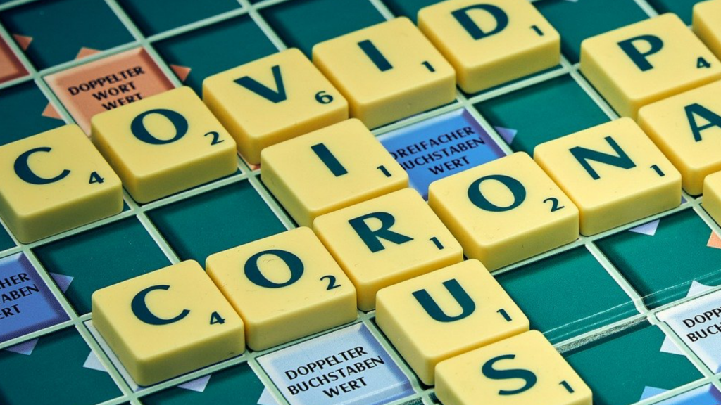 "Covid," "corona," and "virus" spelled out on a scrabble board.