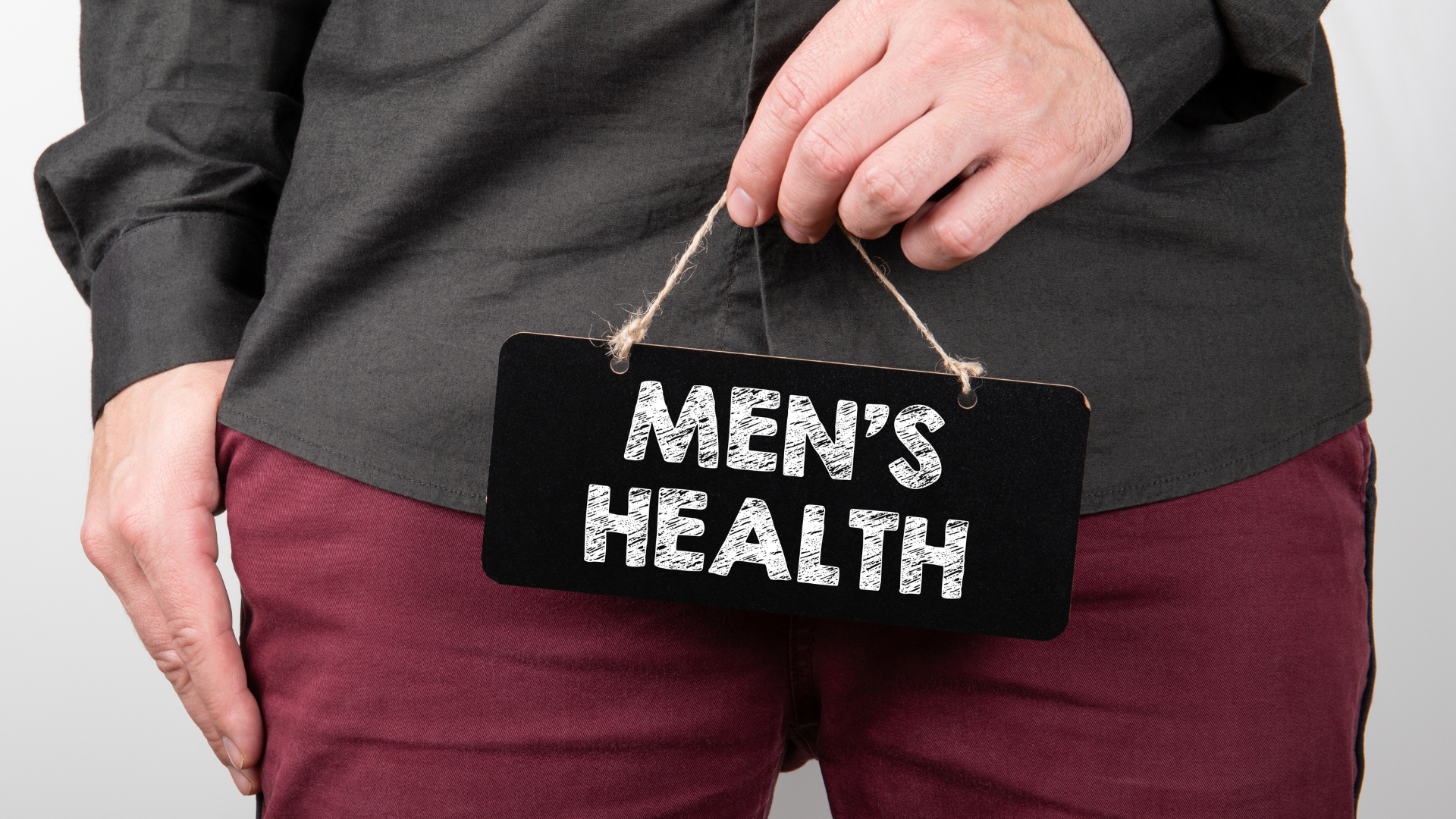 Image of a male's torso region with him holding a sign reading 'Men's health'